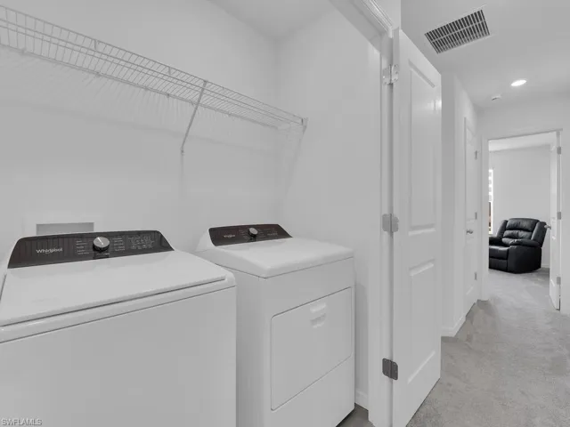 Laundry room with washing machine and clothes dryer, laundry area, light colored carpet, visible vents, and recessed lighting