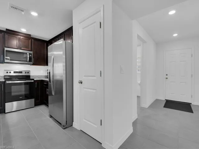 Kitchen featuring recessed lighting, light tile patterned floors, visible vents, dark brown cabinetry, and appliances with stainless steel finishes