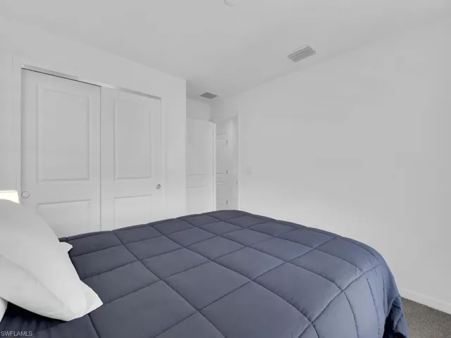 Carpeted bedroom with a closet, baseboards, and visible vents