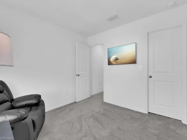 Living area with carpet flooring, baseboards, and visible vents
