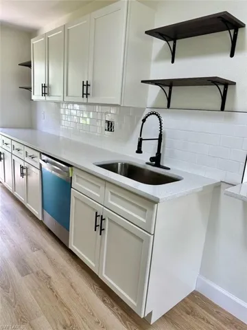 Kitchen featuring white cabinets, light hardwood / wood-style floors, dishwasher, backsplash, and sink