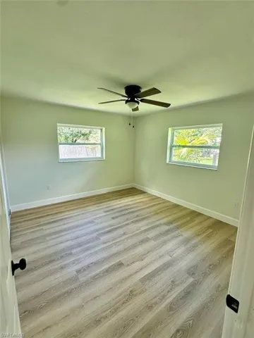 Empty room with ceiling fan, a healthy amount of sunlight, and light hardwood / wood-style flooring