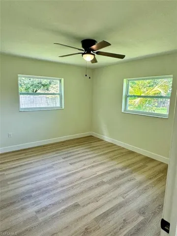 Empty room with a wealth of natural light, ceiling fan, and light wood-type flooring