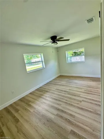 Spare room with a healthy amount of sunlight, wood-type flooring, ceiling fan, and a skylight