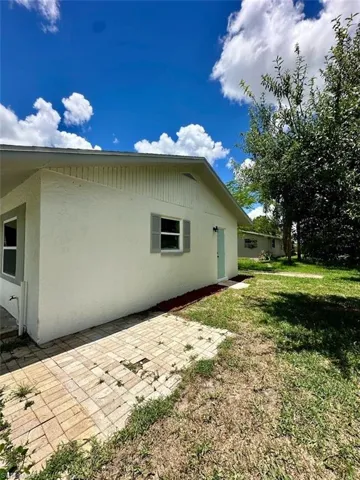 View of property exterior with a yard and a patio