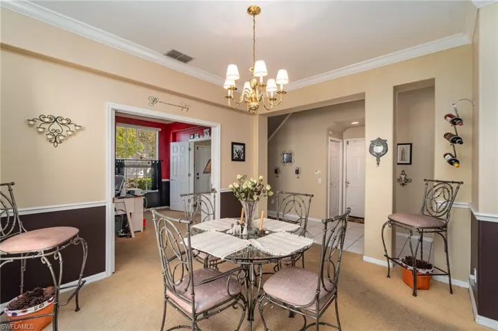 Dining space with a notable chandelier, light carpet, and crown molding