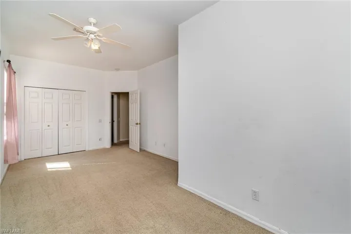 Unfurnished bedroom featuring light carpet, a closet, and ceiling fan