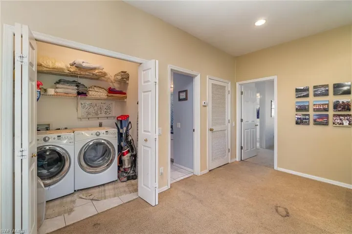 Clothes washing area featuring light carpet and washing machine and clothes dryer
