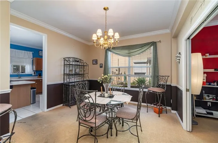 Dining space with ornamental molding, a chandelier, light colored carpet, and sink