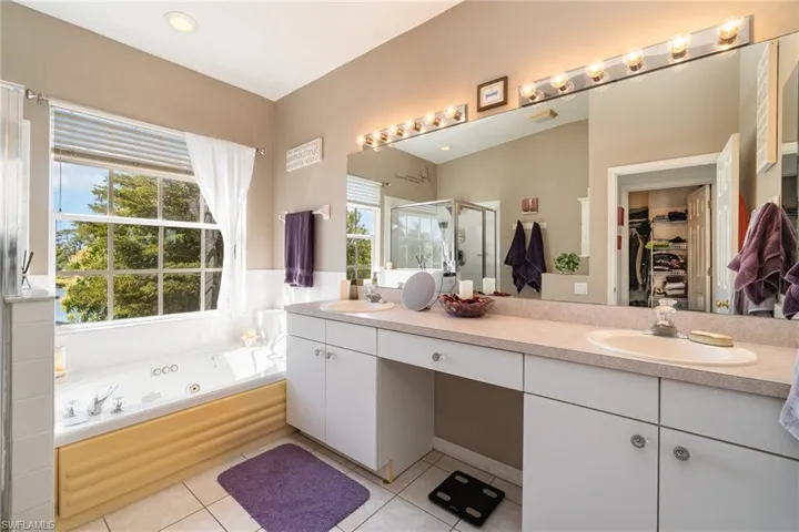 Bathroom featuring vanity, tile patterned floors, plus walk in shower, and plenty of natural light