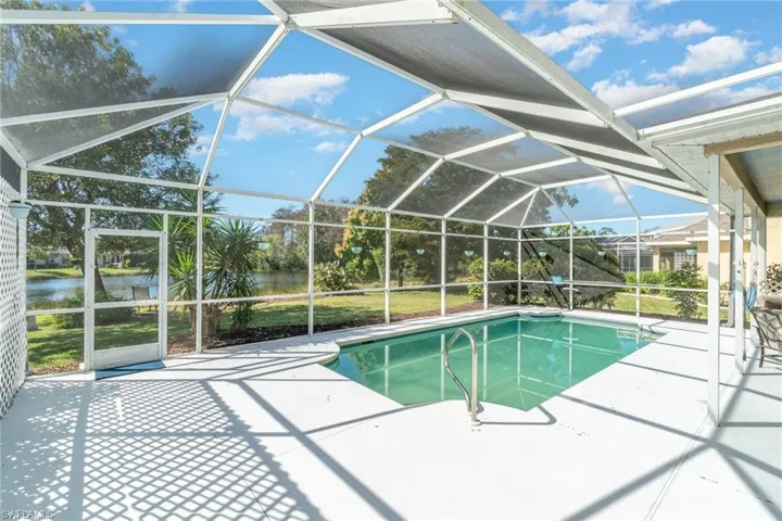 View of swimming pool featuring a patio, a water view, and glass enclosure