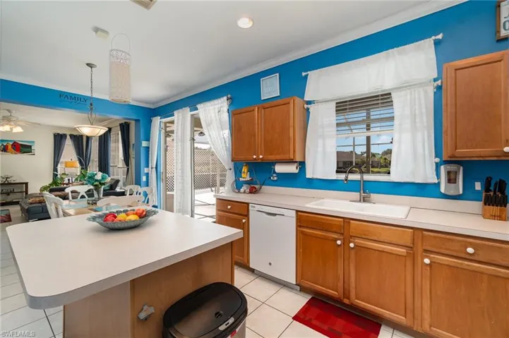 Kitchen featuring light tile patterned flooring, sink, a kitchen island, white dishwasher, and hanging light fixtures