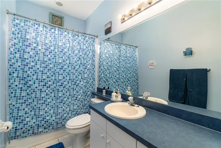 Bathroom featuring vanity, a shower with curtain, toilet, and tile patterned floors
