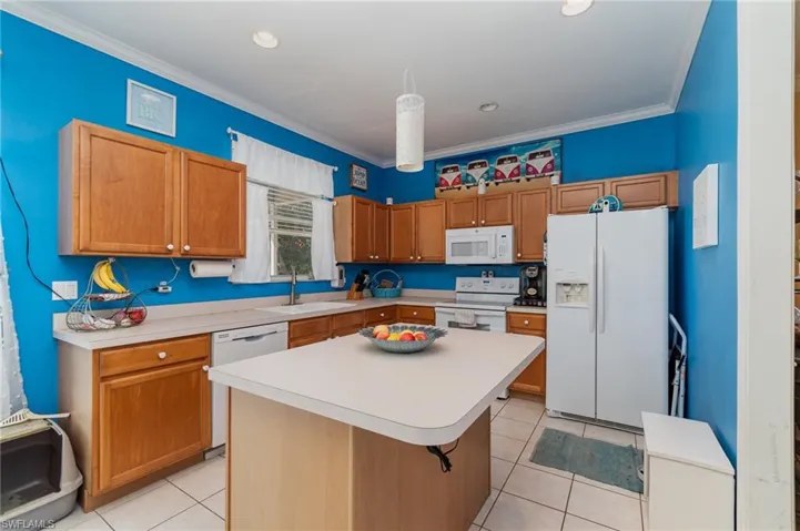 Kitchen with white appliances, crown molding, sink, and a kitchen island