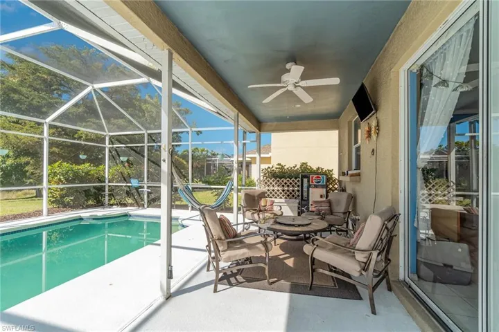 View of swimming pool featuring a patio, ceiling fan, and glass enclosure