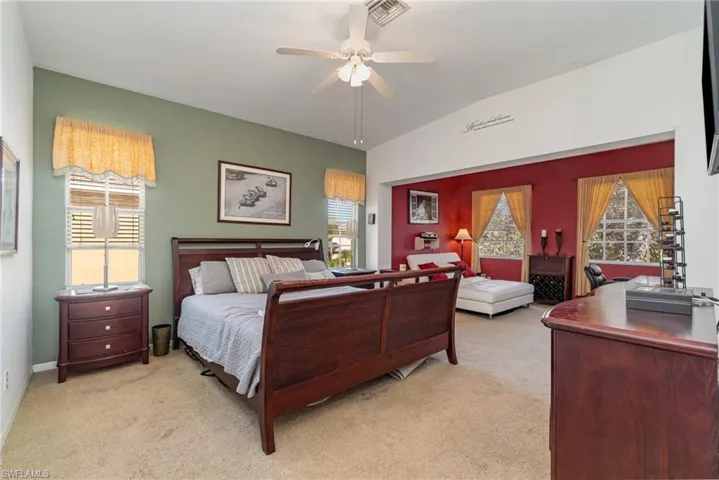 Bedroom with ceiling fan, light carpet, and multiple windows