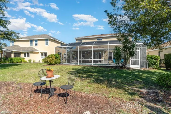 Back of property featuring a lawn and glass enclosure