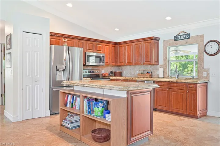 Kitchen with a center island, brown cabinets, stainless steel appliances, light stone counters, and backsplash