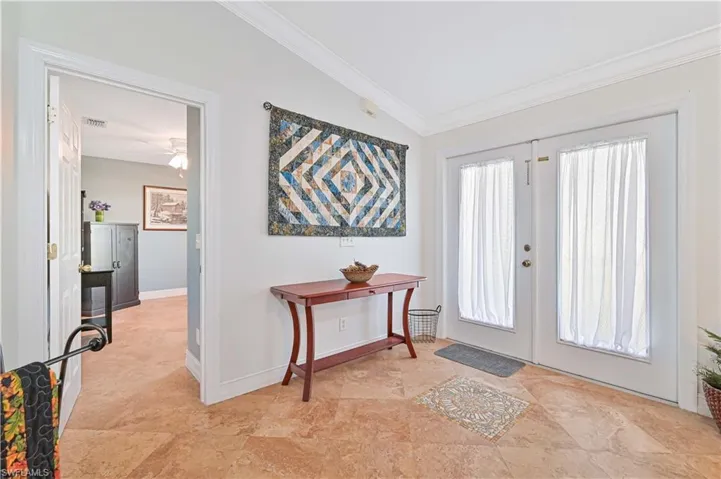 Foyer with lofted ceiling, french doors, and crown molding