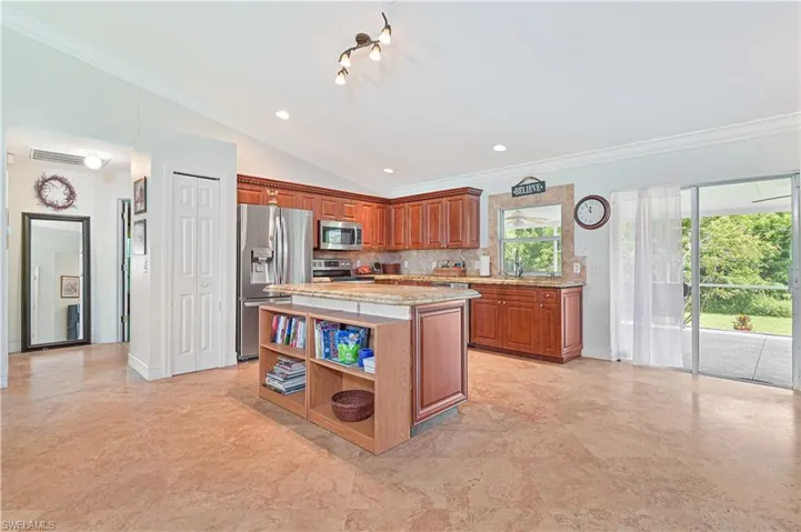 Kitchen with brown cabinetry, ornamental molding, a center island, appliances with stainless steel finishes, and recessed lighting