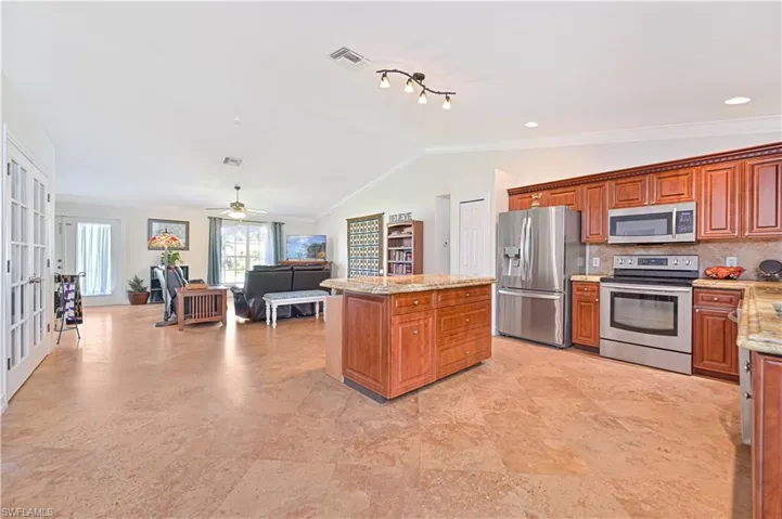 Kitchen featuring stainless steel appliances, backsplash, brown cabinets, open floor plan, and french doors