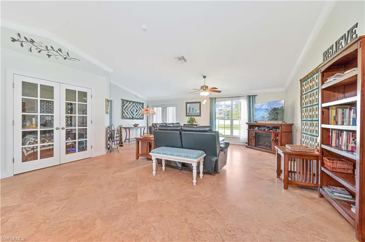 Living room featuring ornamental molding, vaulted ceiling, french doors, and a fireplace