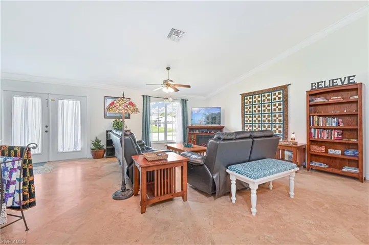 Living area featuring ornamental molding, ceiling fan, vaulted ceiling, and french doors