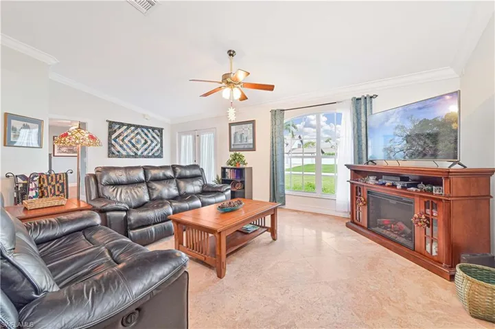 Living area featuring ornamental molding, a ceiling fan, and lofted ceiling