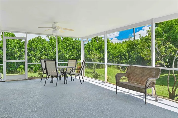 Sunroom / solarium with ceiling fan and view of wooded area