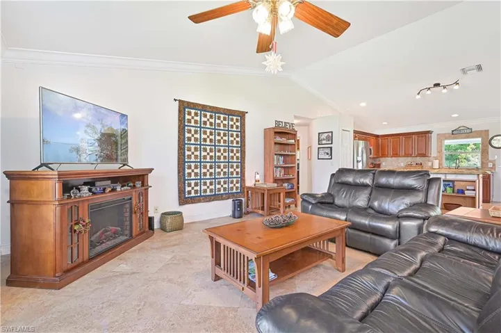 Living room featuring ornamental molding, lofted ceiling, and a ceiling fan