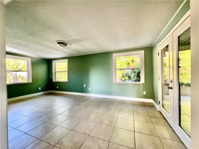 Tiled empty room with french doors and a textured ceiling