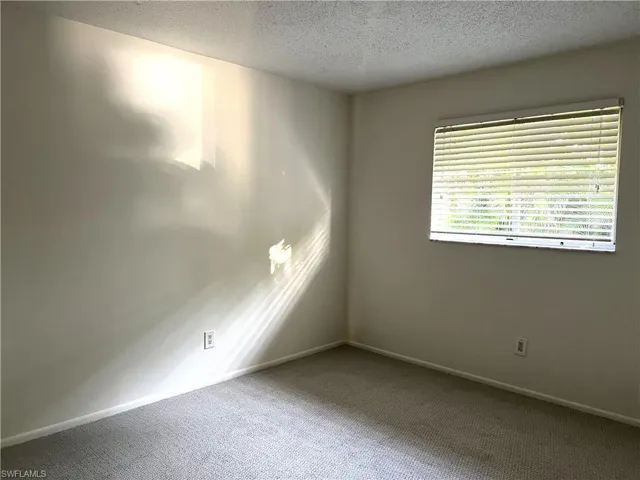 Carpeted empty room featuring a textured ceiling