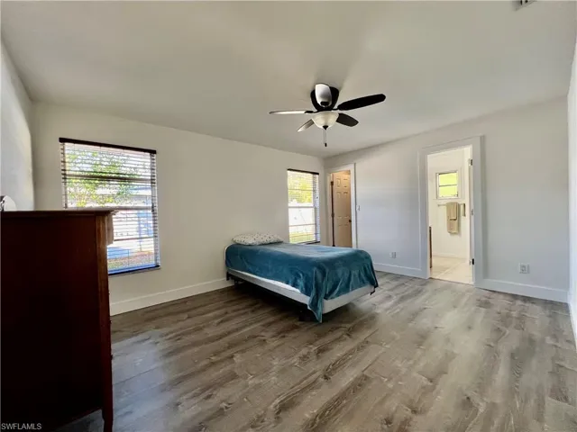 Bedroom with wood-type flooring, connected bathroom, and ceiling fan