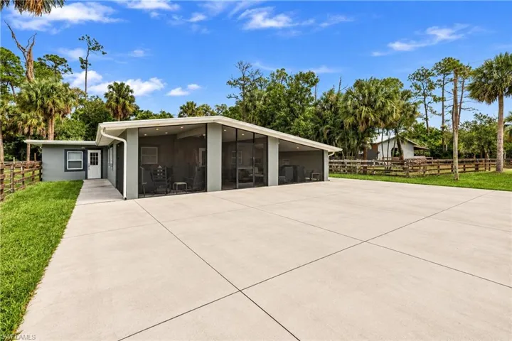 Spacious concrete driveway, screened-in patio, stucco exterior, and a white entry door