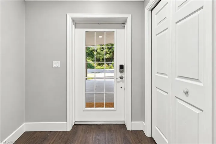 Wood-finish flooring, white trim, light gray wall finish, and a glass-paneled entry door with smart lock technology