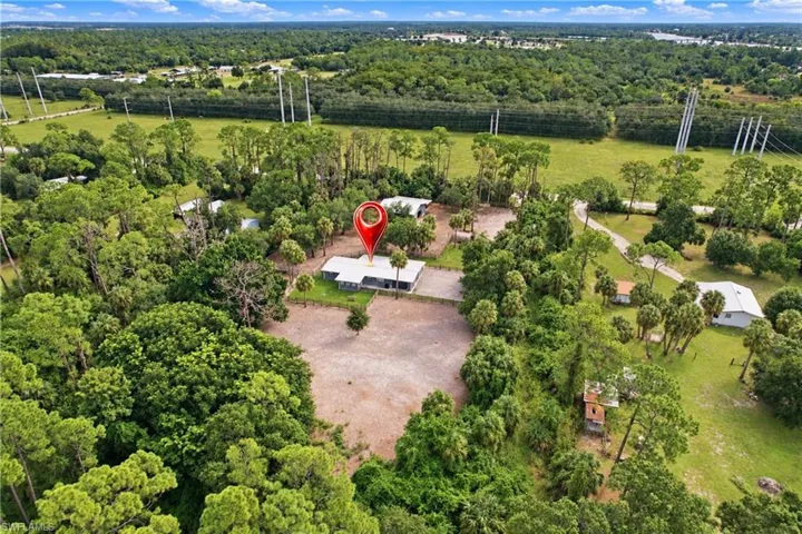 Expansive property featuring a single-story residence, mature trees, open land, and a surrounding natural landscape