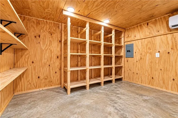 Wood-paneled room featuring extensive built-in shelving, a dedicated storage rack, and overhead lighting