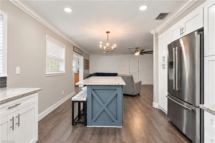 Kitchen featuring white cabinetry, granite countertops, a stainless steel refrigerator, and wood-finish flooring