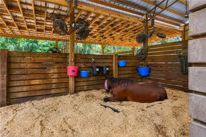 Open-air stall with a wood-slat enclosure and metal roof water source at each stall