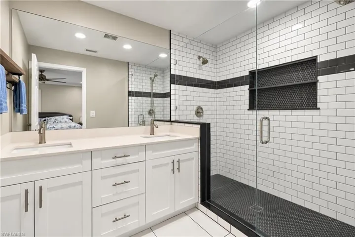 Dual vanity with white cabinetry and light-toned countertops and large walk-in, recently redone master bath shower