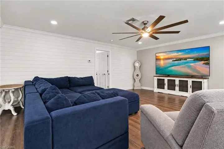 Wood-finish flooring with white shiplap accent wall additional view of open concept living room area
