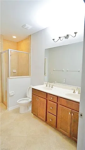 Bathroom featuring tile patterned floors, vanity, toilet, and a shower with door
