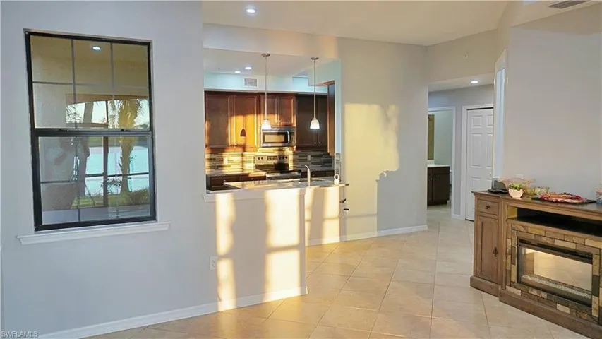 Kitchen featuring backsplash, sink, light tile patterned floors, appliances with stainless steel finishes, and decorative light fixtures