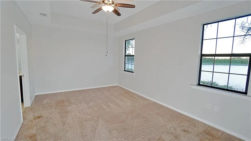 Spare room featuring a healthy amount of sunlight, ceiling fan, and light colored carpet