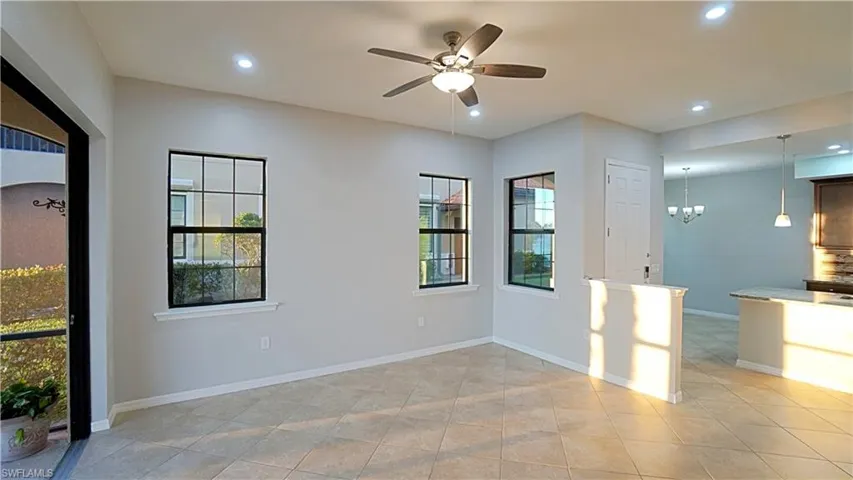 Unfurnished room with ceiling fan with notable chandelier, plenty of natural light, and light tile patterned flooring