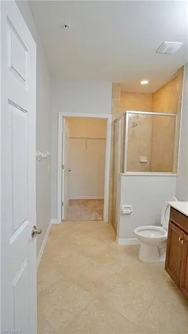 Bathroom featuring tile patterned floors, vanity, toilet, and a shower with door