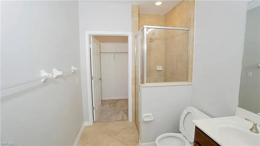 Bathroom featuring tile patterned floors, vanity, toilet, and walk in shower