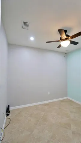 Empty room featuring ceiling fan and light tile patterned flooring