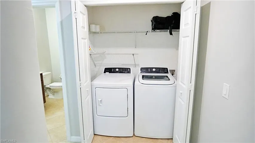 Laundry area with washer and dryer and light tile patterned floors