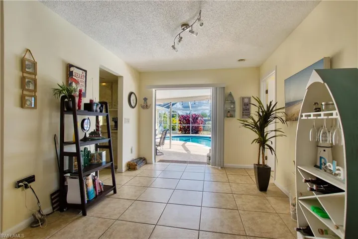 Entryway featuring a sunroom, rail lighting, tile patterned floors, and a textured ceiling